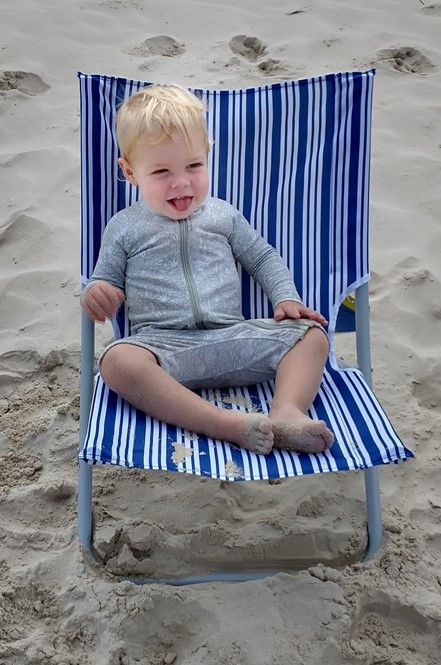 aussie kid on beach enjoying the sunshine in deck chair smiling
